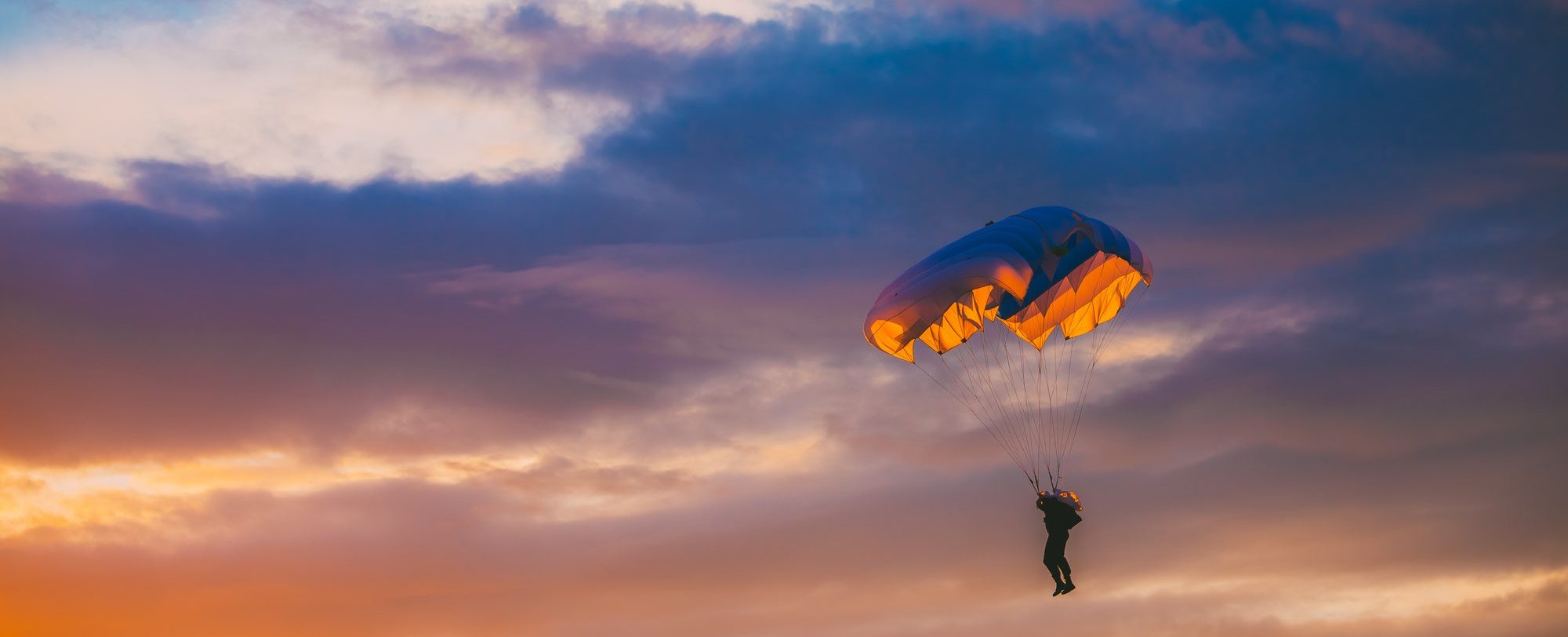 Skydiver On Colorful Parachute In Sunny Sky